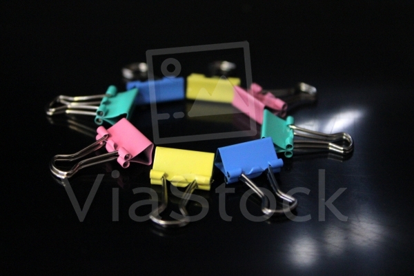 Multi-colored clips that form a circle to illuminate a black space.