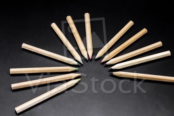 Twelve crayons in a semicircle on a black background